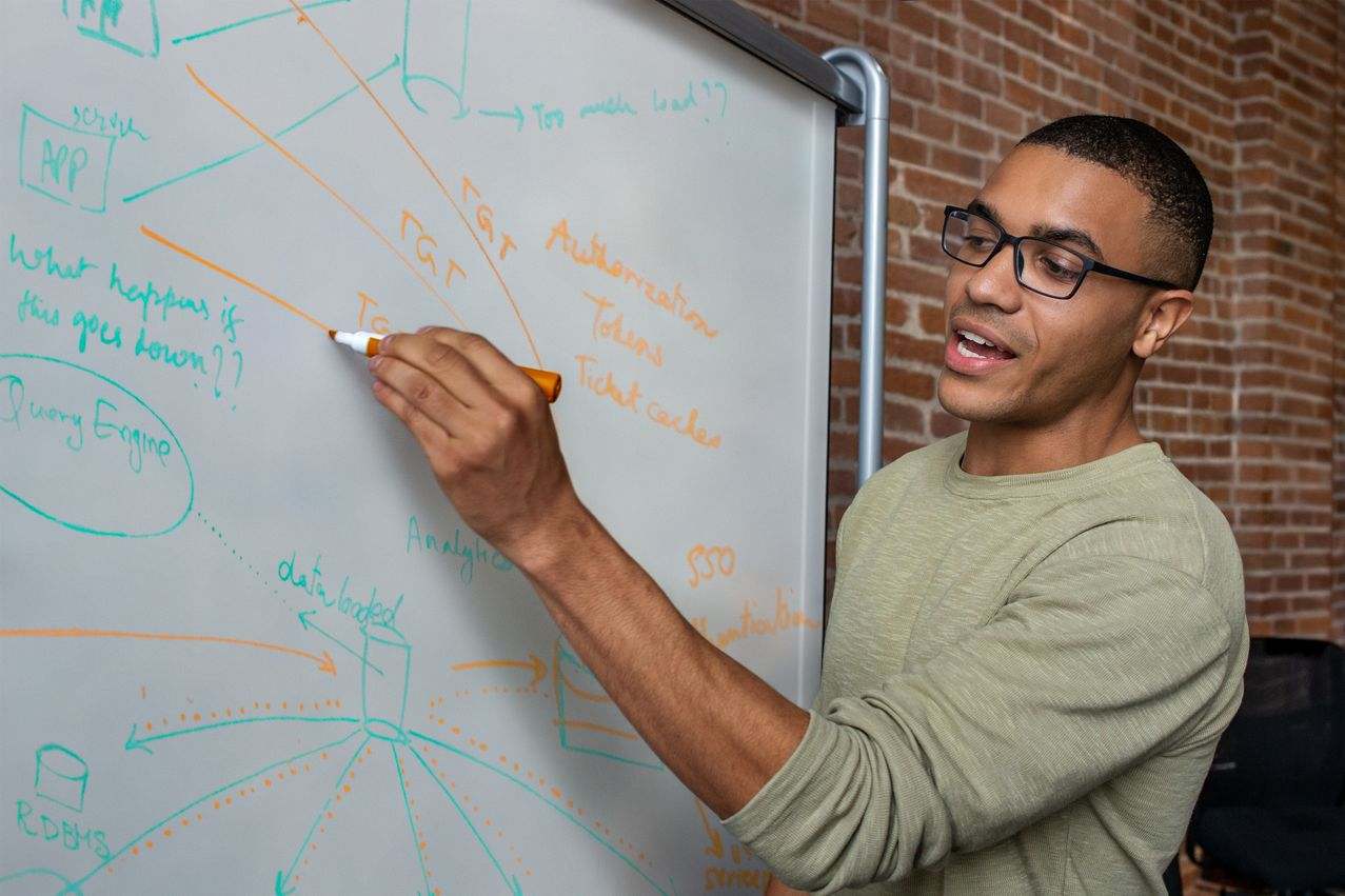 Black cloud engineer presenting migration milestones on a whiteboard