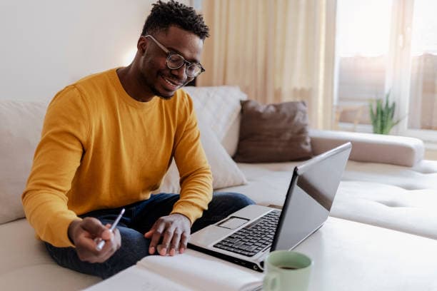 Black professional conducting research and writing articles on a laptop in a Lagos office