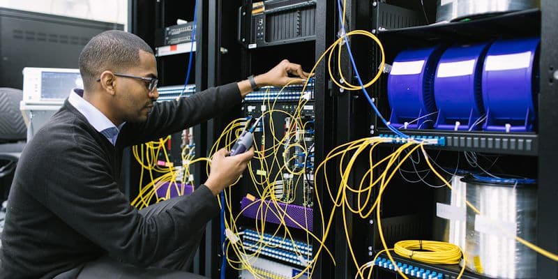 Black smart-systems engineer monitoring live IoT dashboards in a control room